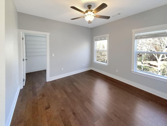 empty room with ceiling fan and dark wood-type flooring