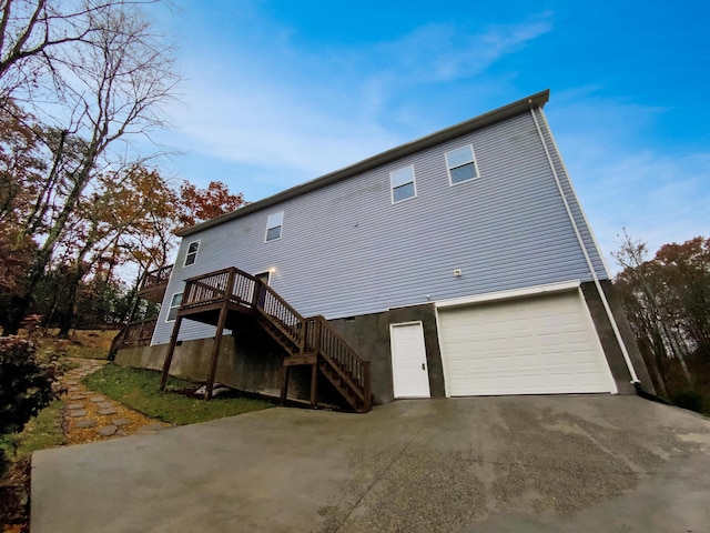 rear view of property featuring a garage and a wooden deck