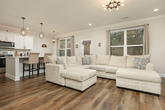 living room featuring dark hardwood / wood-style flooring, crown molding, and an inviting chandelier