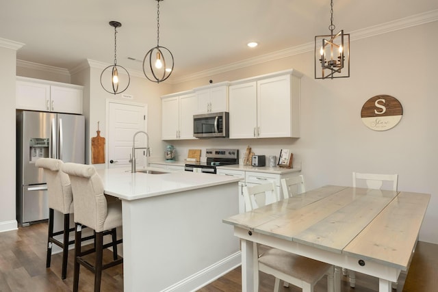 kitchen featuring white cabinetry, sink, pendant lighting, a kitchen island with sink, and appliances with stainless steel finishes