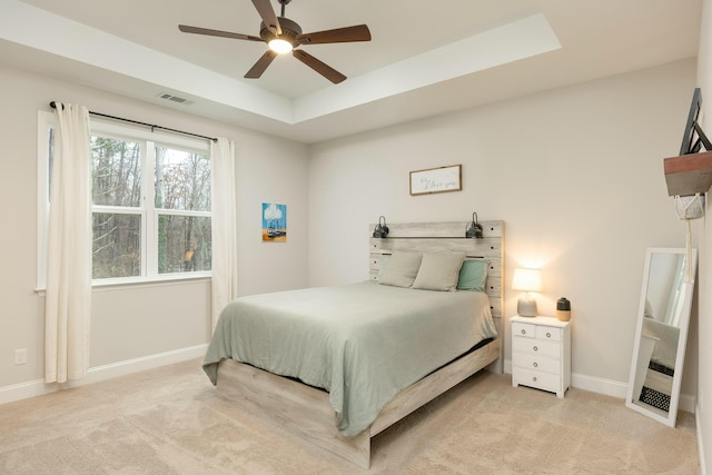 carpeted bedroom with ceiling fan and a tray ceiling