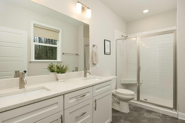 bathroom with vanity, toilet, and a shower with door