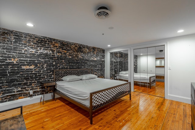 bedroom with hardwood / wood-style floors, multiple closets, and recessed lighting