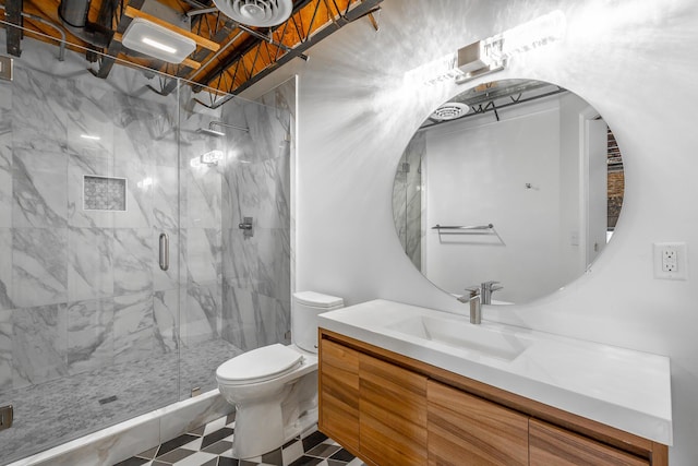 bathroom featuring toilet, a marble finish shower, and vanity