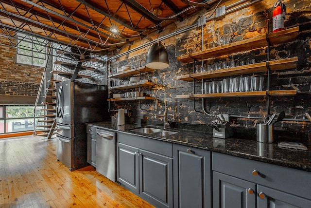 bar featuring a sink, light wood-style floors, appliances with stainless steel finishes, indoor wet bar, and plenty of natural light