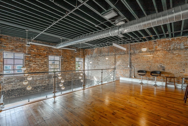 interior space with brick wall and hardwood / wood-style flooring