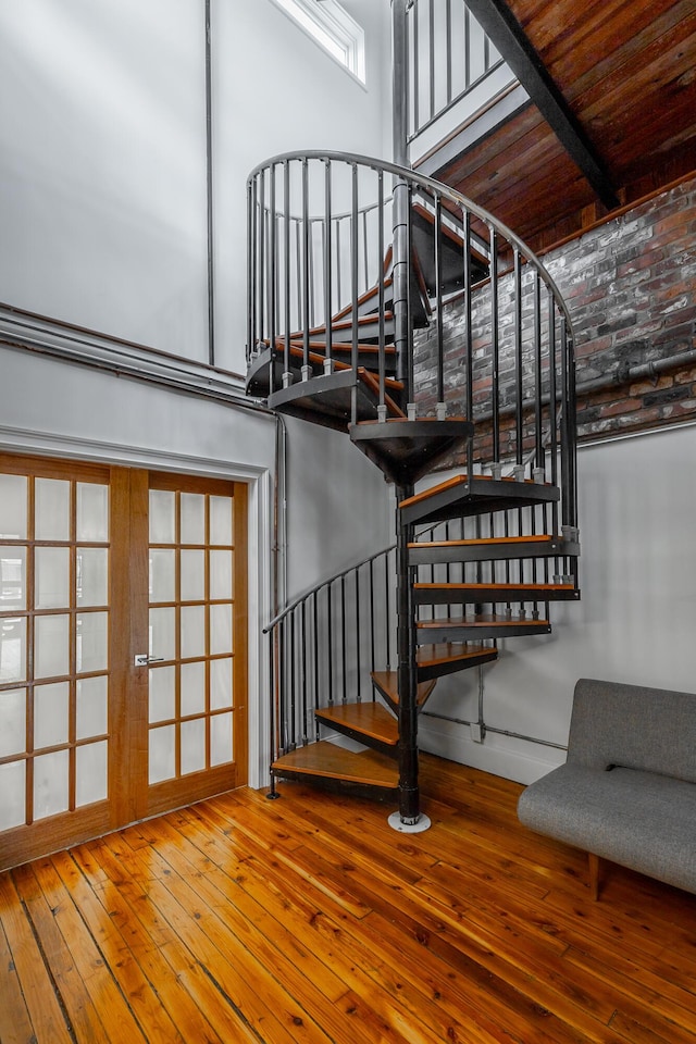 stairway featuring a high ceiling, hardwood / wood-style floors, and french doors