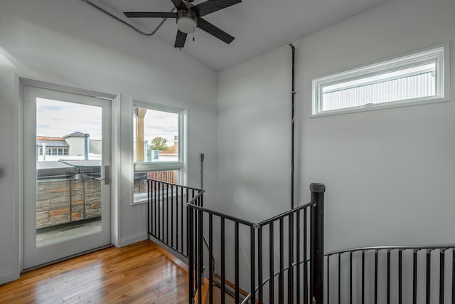 staircase featuring a healthy amount of sunlight, a ceiling fan, wood finished floors, and lofted ceiling