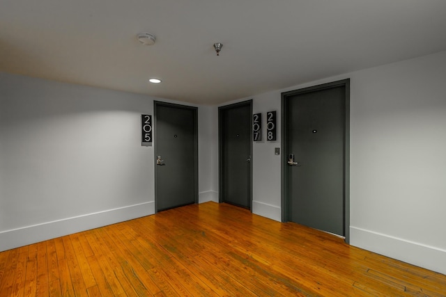 unfurnished room with recessed lighting, wood-type flooring, and baseboards