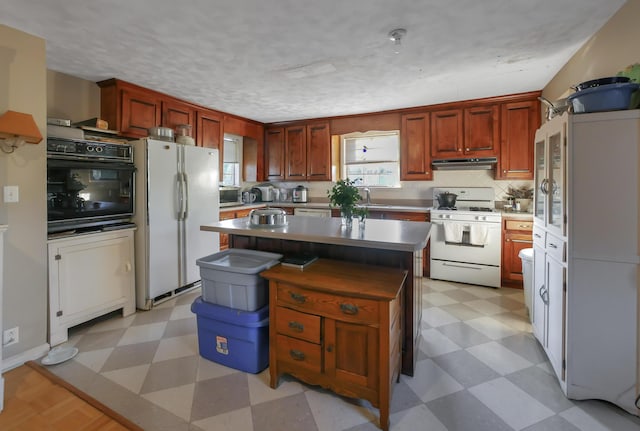 kitchen with a textured ceiling, white appliances, a center island, and sink