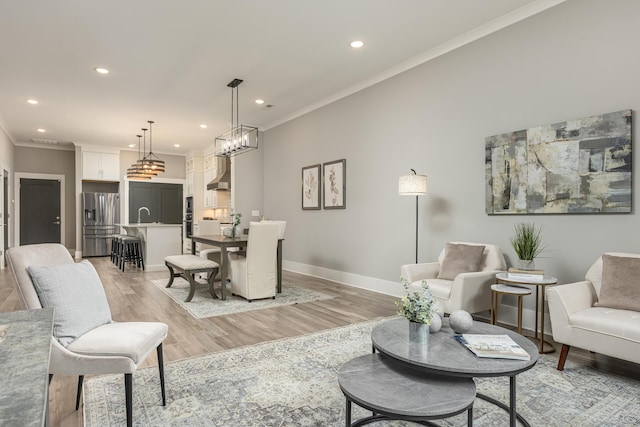 living room with ornamental molding, light hardwood / wood-style flooring, and sink