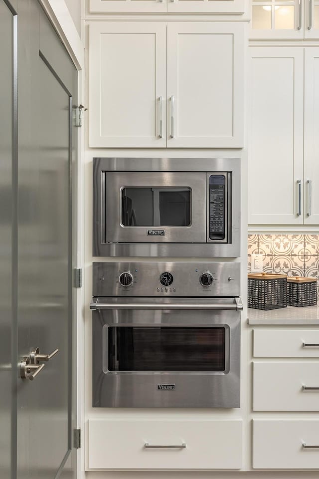 kitchen with appliances with stainless steel finishes, white cabinetry, and backsplash