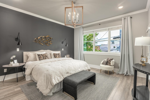 bedroom featuring a notable chandelier, light hardwood / wood-style floors, and crown molding