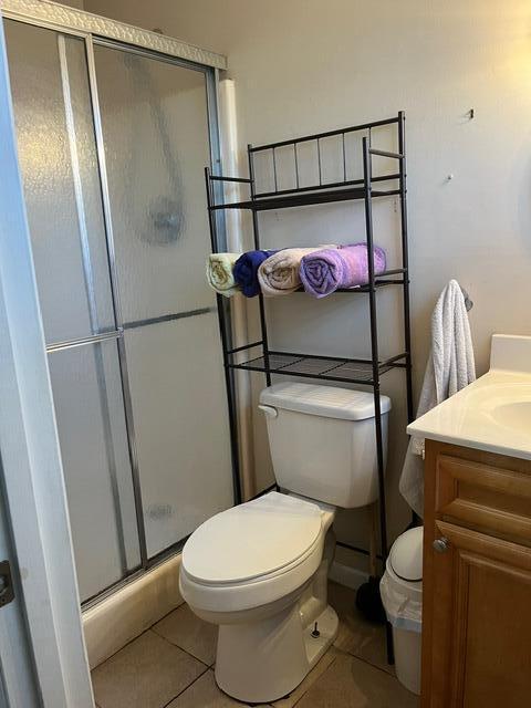 bathroom with tile patterned floors, vanity, toilet, and a shower with door