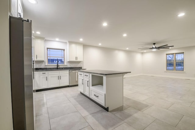 kitchen featuring stainless steel appliances, ceiling fan, a center island, white cabinetry, and light tile patterned flooring