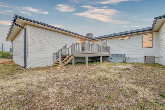 rear view of house with central AC unit, a deck, and a lawn