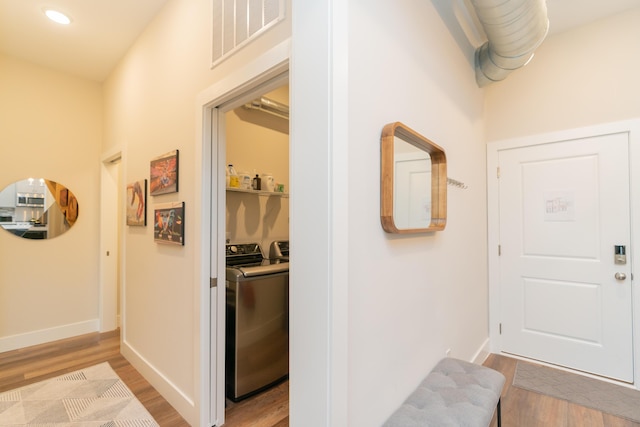 hall with washing machine and clothes dryer and light hardwood / wood-style flooring