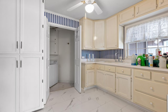 kitchen featuring ceiling fan, sink, ornamental molding, and washer / dryer