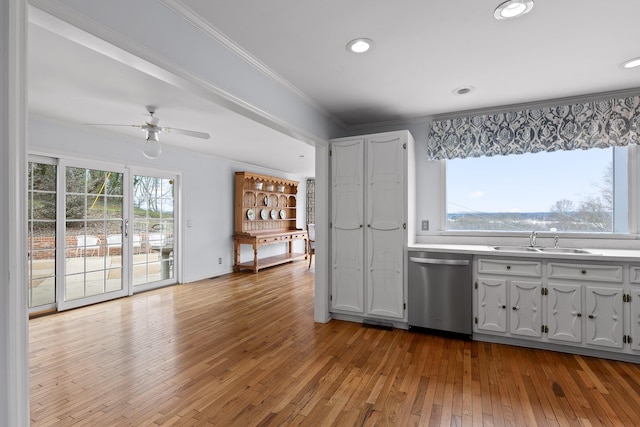 kitchen with white cabinets, sink, stainless steel dishwasher, ceiling fan, and ornamental molding