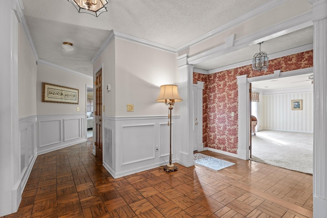 entrance foyer with dark parquet flooring, an inviting chandelier, a textured ceiling, and ornamental molding