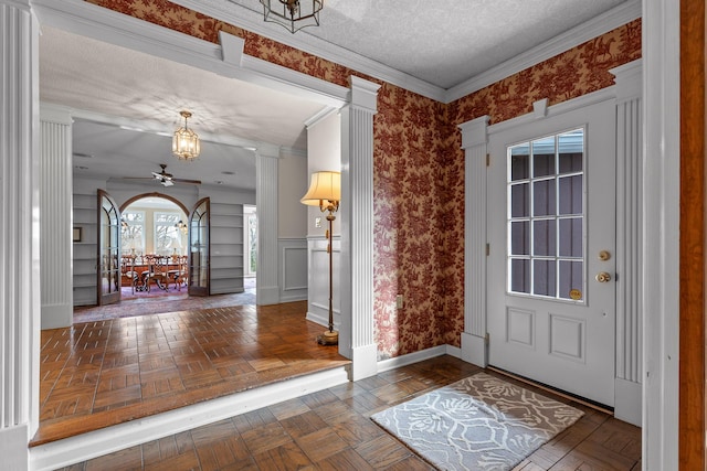 foyer entrance featuring dark parquet flooring, crown molding, and ceiling fan with notable chandelier