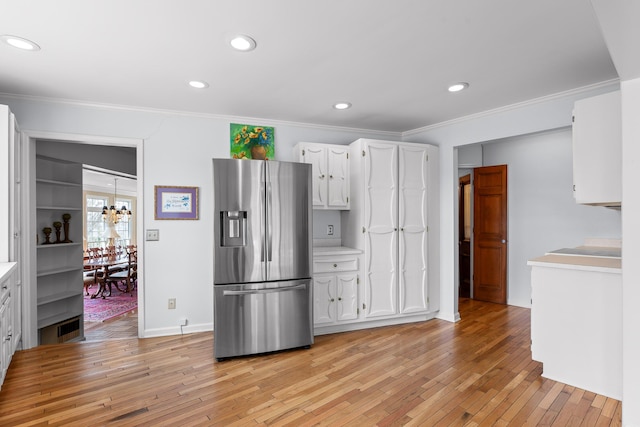 kitchen featuring light hardwood / wood-style flooring, stainless steel fridge, ornamental molding, a notable chandelier, and white cabinetry