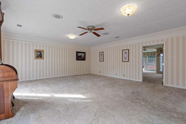 carpeted spare room with ceiling fan, ornamental molding, and a textured ceiling