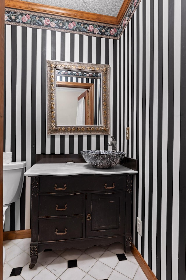 bathroom with tile patterned floors, vanity, toilet, and a textured ceiling