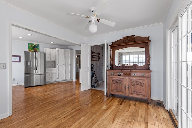 kitchen with ceiling fan, light hardwood / wood-style flooring, stainless steel fridge, white cabinets, and ornamental molding