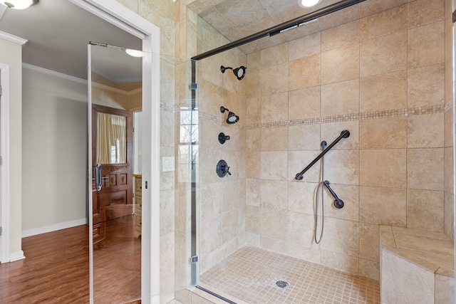 bathroom featuring wood-type flooring, a shower with shower door, and crown molding