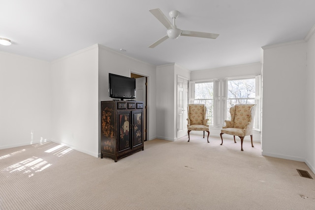 sitting room featuring light carpet, ceiling fan, and ornamental molding