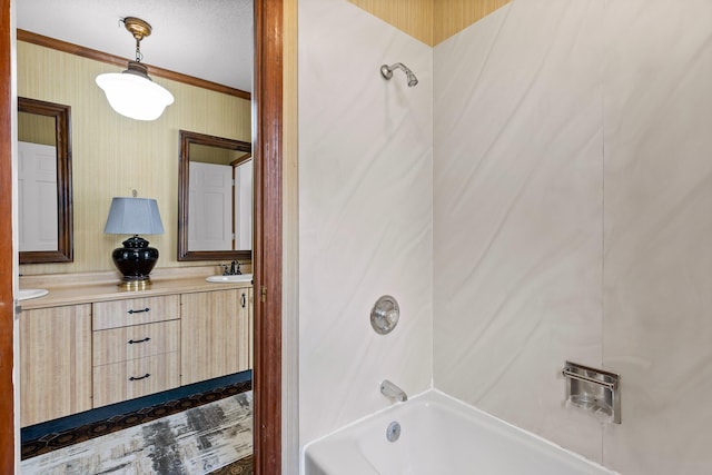 bathroom featuring a textured ceiling, vanity, bathing tub / shower combination, and ornamental molding