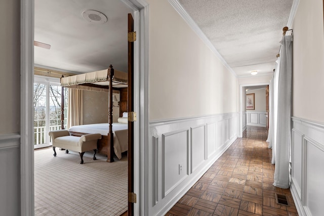 corridor featuring a textured ceiling, light parquet floors, and crown molding