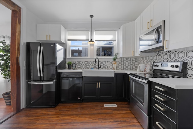 kitchen featuring decorative backsplash, dark hardwood / wood-style floors, decorative light fixtures, black appliances, and sink