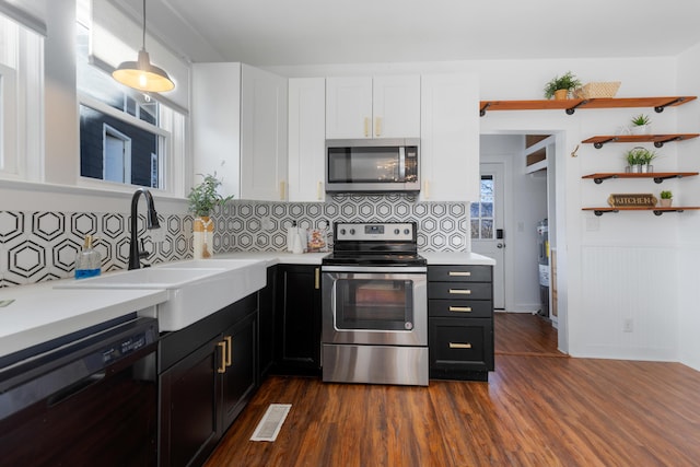 kitchen with appliances with stainless steel finishes, tasteful backsplash, dark wood-type flooring, hanging light fixtures, and sink