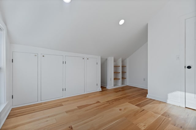 additional living space featuring light wood-type flooring and vaulted ceiling