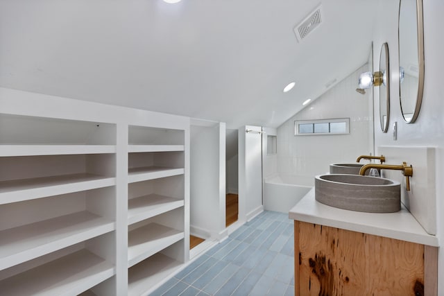 bathroom with vanity, a bath, and vaulted ceiling