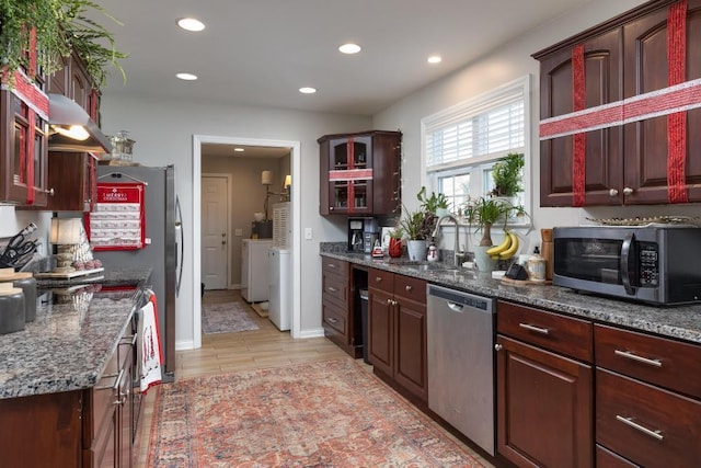 kitchen featuring dark stone countertops, sink, appliances with stainless steel finishes, and light hardwood / wood-style flooring