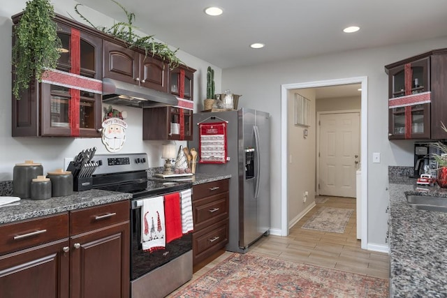 kitchen featuring dark brown cabinetry, dark stone countertops, light wood-type flooring, and appliances with stainless steel finishes