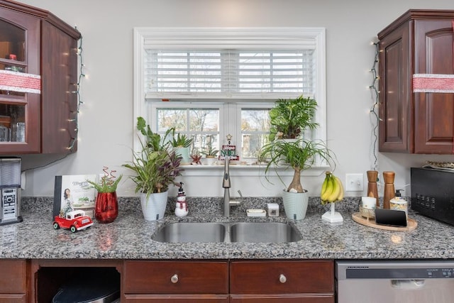 kitchen featuring light stone counters, stainless steel dishwasher, a wealth of natural light, and sink