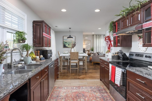 kitchen featuring sink, stainless steel appliances, dark stone countertops, pendant lighting, and light hardwood / wood-style floors