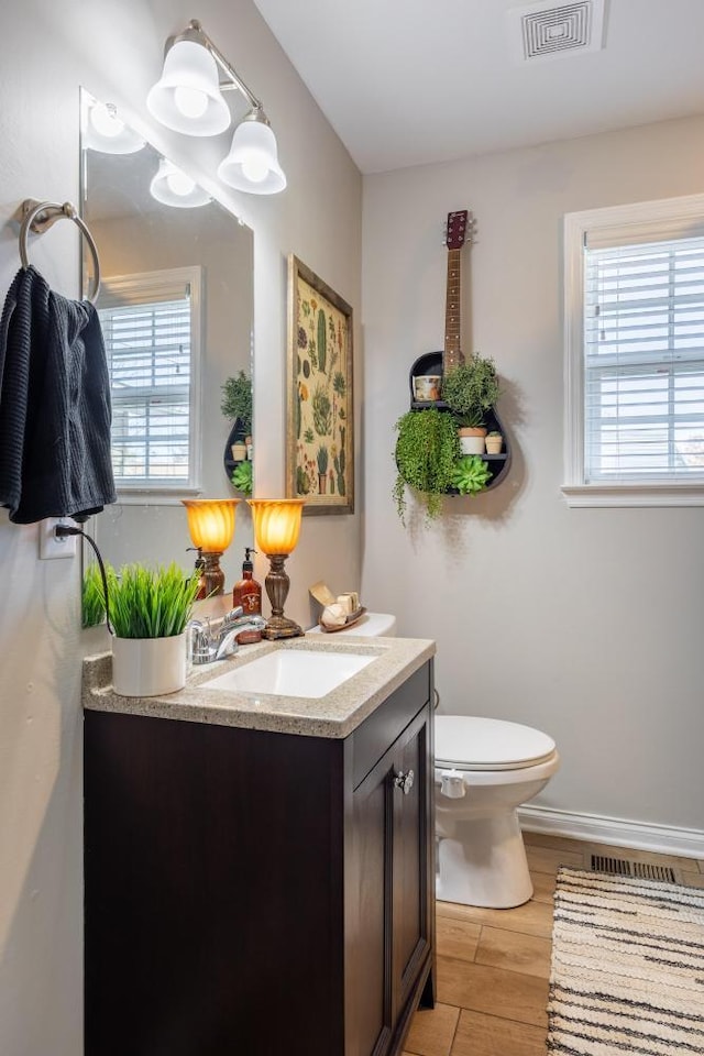 bathroom featuring wood-type flooring, vanity, toilet, and plenty of natural light