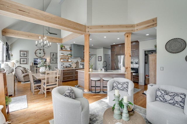 living room with high vaulted ceiling, sink, light hardwood / wood-style flooring, beamed ceiling, and a notable chandelier