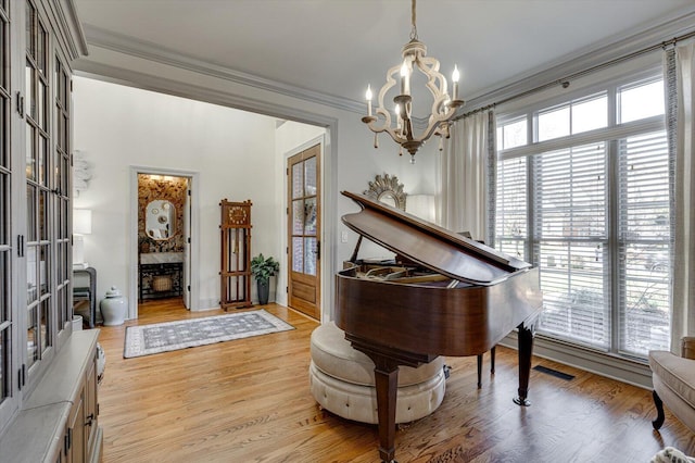 miscellaneous room with a chandelier, light hardwood / wood-style flooring, and crown molding