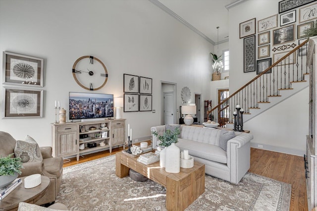 living room with a high ceiling, crown molding, and hardwood / wood-style floors