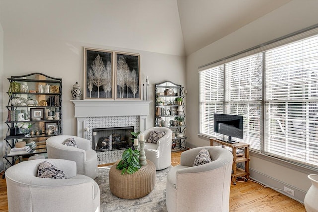 living room featuring a tile fireplace, wood-type flooring, and lofted ceiling