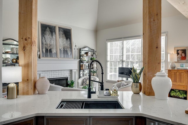 room details featuring light stone counters, sink, and a tiled fireplace