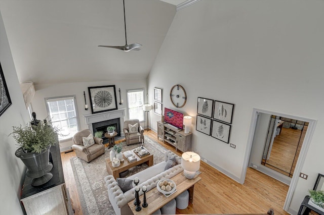 living room with ceiling fan, high vaulted ceiling, and light hardwood / wood-style floors