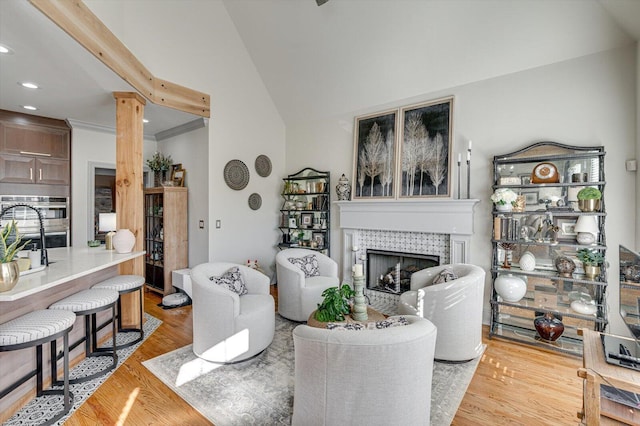 living room featuring vaulted ceiling with beams, wood-type flooring, a fireplace, and ornamental molding