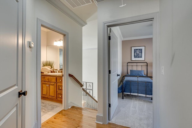 hallway featuring light hardwood / wood-style floors, sink, and crown molding